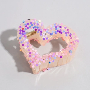 Detail of a pink heart hair claw clip with colorful sequins and golden metal spring