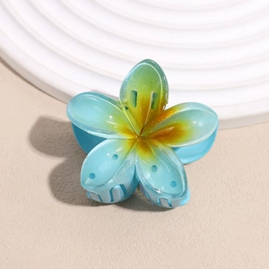 Macro detail of a gradient blue frangipani hair claw clip with realistic floral resin texture