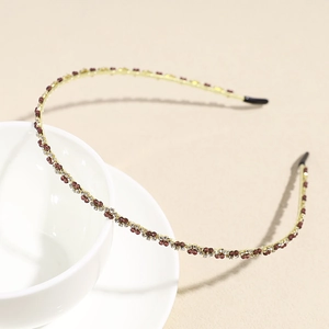 Close-up of golden crystal headband with red and white rhinestones and black ear tips