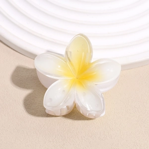 Close-up of a white and yellow frangipani flower hair claw clip with detailed resin texture