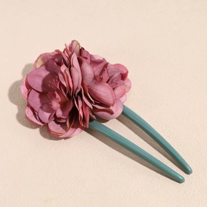 Detail showing the dark pink fabric flower petals and green U-shaped hair pin fork
