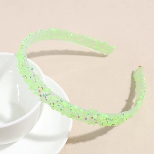 Détail d'un serre-tête vert néon avec paillettes colorées et dents antidérapantes