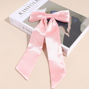 Dettaglio di un grande fiocco in raso rosa con nastri lunghi su una rivista di moda