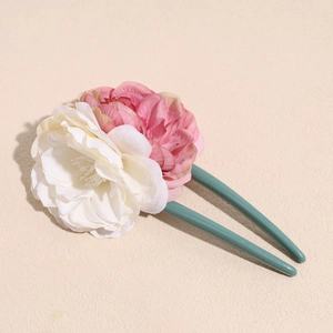 Macro detail of artificial silk rose petals in white and pink on a U-shaped hairpin