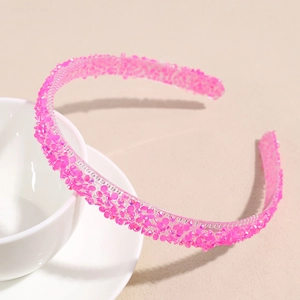 Détail d'un serre-tête rose fuchsia avec des paillettes brillantes et cristaux étincelants