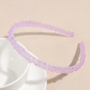Détail d'un serre-tête violet à strass montrant les perles texturées et les dents internes