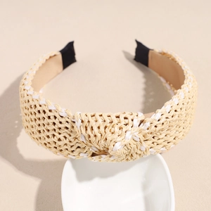 Close-up of beige raffia knotted headband with intricate woven straw texture on ceramic stand