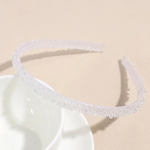 Détail d'un serre-tête blanc translucide avec perles irisées sur une tasse