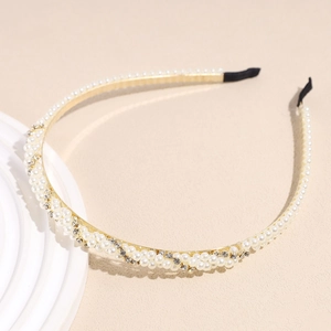 Close-up of pearl and rhinestone headband with gold metal frame and black protective ends