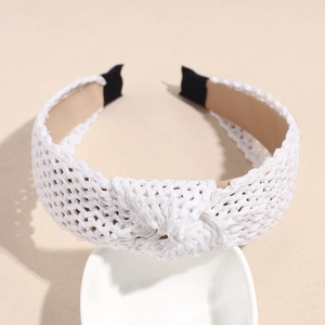 Close-up of white woven raffia headband with twisted knot detail and soft cloth lining