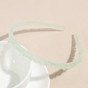 Gros plan d'un serre-tête vert clair perlé avec une texture en résine sur fond beige