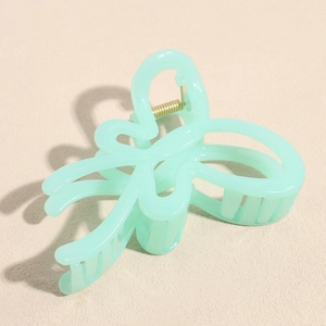 Close-up of mint green butterfly hair claw clip with strong golden metal spring