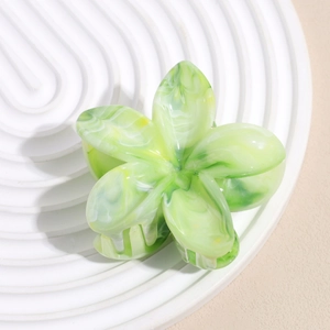 Close-up of a 6cm flower hair claw clip with green marble texture on a white tray