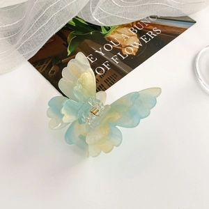 Macro detail of blue and yellow gradient butterfly hair claw clip with golden metal spring