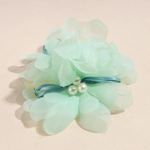 Dettaglio del fermaglio per capelli a fiore in chiffon verde menta con perle e nastro