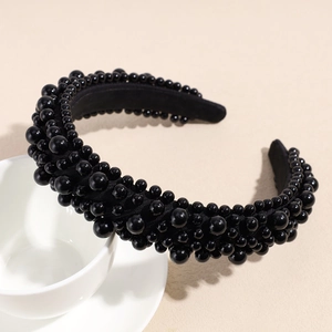 Close-up of elegant black beaded headband with varied pearl sizes on a coffee cup