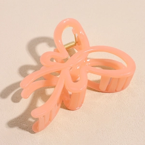 Detail view of large coral pink jelly butterfly hair claw clip with strong gold spring