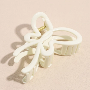 Detail of a creamy beige butterfly hair claw clip with a glossy finish and gold spring