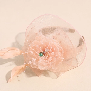 Detail of pink mesh veil headband featuring floral petals, delicate feathers and beadwork