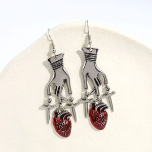 Orecchini gotici argentati con cuore rosso e spade su un piatto di ceramica