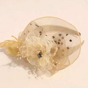Close-up of champagne fascinator with mesh veil, silk flower, and pearl tassels