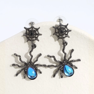Dettaglio degli orecchini pendenti a ragnatela con gemma blu per un look gotico chic