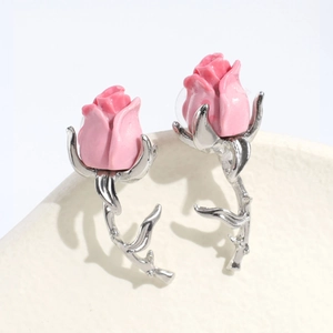 Dettaglio macro di orecchino a rosa rosa con gambo spinato argento su base bianca