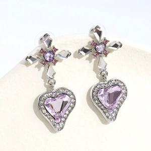 Dettaglio ravvicinato di orecchini a croce con cuore di cristallo viola e argento