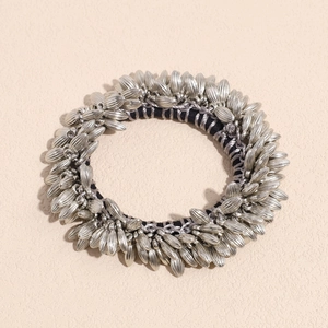 Macro detail of wheat ear patterned silver metal beads on a black elastic hair tie