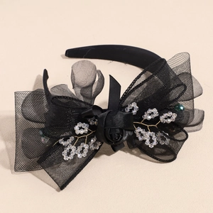 Detail of black velvet headband with large mesh bow and crystal leaf decorations
