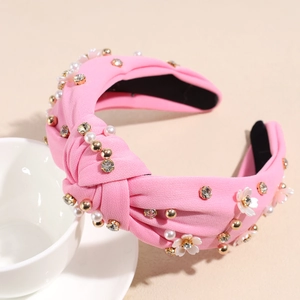 Dettaglio cerchietto in tessuto rosa con nodi, fiori bianchi, perle e strass