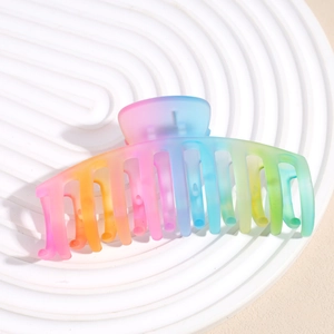 Macro detail of the gradient rainbow hair claw clip with matte texture on a tray