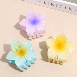 Three gradient plumeria hair claw clips in purple, blue and yellow for summer hairstyles
