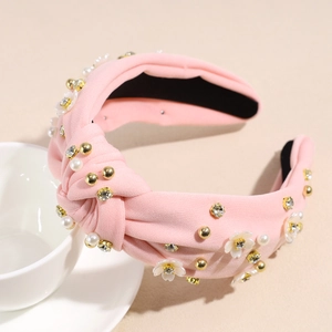 Dettaglio di un cerchietto annodato rosa con fiori bianchi, perle e cristalli