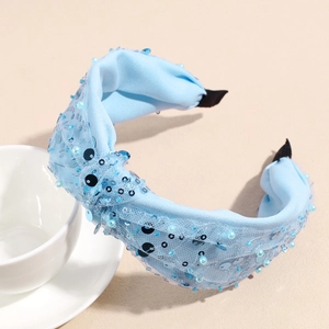 Dettaglio del cerchietto in rete azzurra con paillettes scintillanti e perle fini