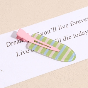 Detail of pink metal hair clip with blue and green striped acrylic plate on light background