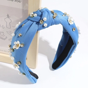 Dettaglio del cerchietto blu con fiori bianchi, perle e strass lucidi su tessuto annodato