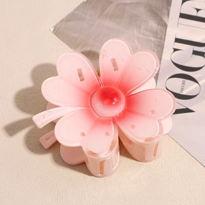 Vue latérale de la pince à cheveux en forme de fleur rose dégradé sur fond texturé