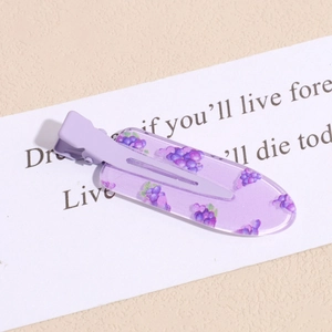 Detail of pink-purple resin hair clip with grape pattern on a textured background