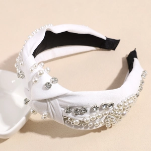 Détail d'un large bandeau élégant avec perles blanches et strass brillants sur satin blanc