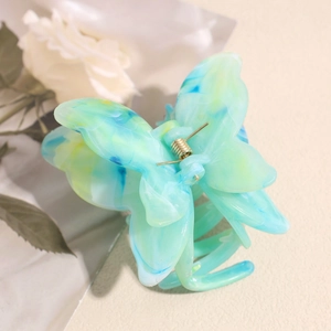 Détail de la pince à cheveux papillon avec texture marbrée verte et ressort doré