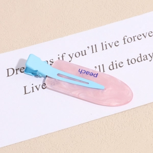 Macro view of pink translucent resin hair clip with blue peach text on display card