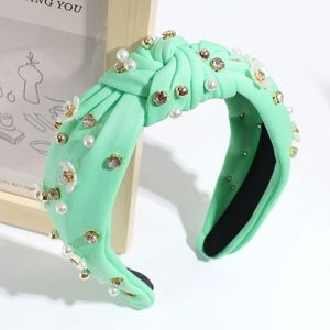 Dettaglio fascia annodata verde menta con perle, strass e accenti floreali in 3D