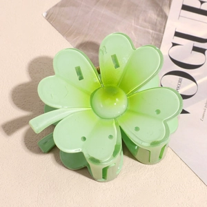 Détail d'une pince à cheveux fleurie vert clair avec texture mate sur fond beige