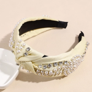 Détail du serre-tête en satin jaune avec nœud en tissu et perles et strass incrustés