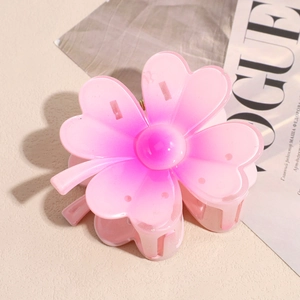 Gros plan détaillé d'une pince à cheveux florale dégradé rose sur un fond de magazine de mode