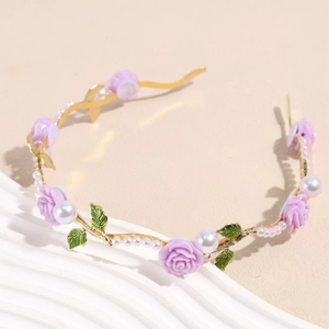 Detailaufnahme des goldenen Blumenstirnbands mit lila Harzrosen und weißen Perlen