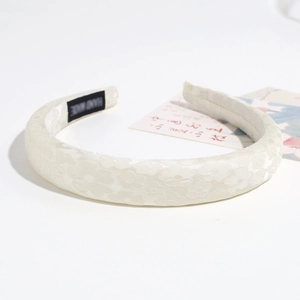 Dettaglio cerchietto imbottito bianco crema con trama jacquard floreale ed etichetta