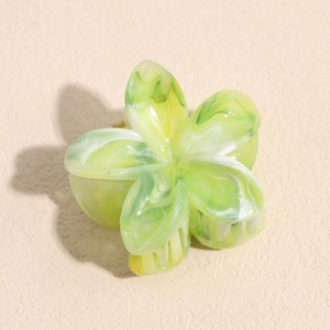 Dettaglio di un fermaglio per capelli a fiore in marmo verde con trama in acetato