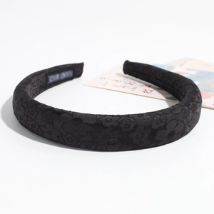 Dettaglio del cerchietto imbottito con trama jacquard nera ed etichetta fatta a mano
